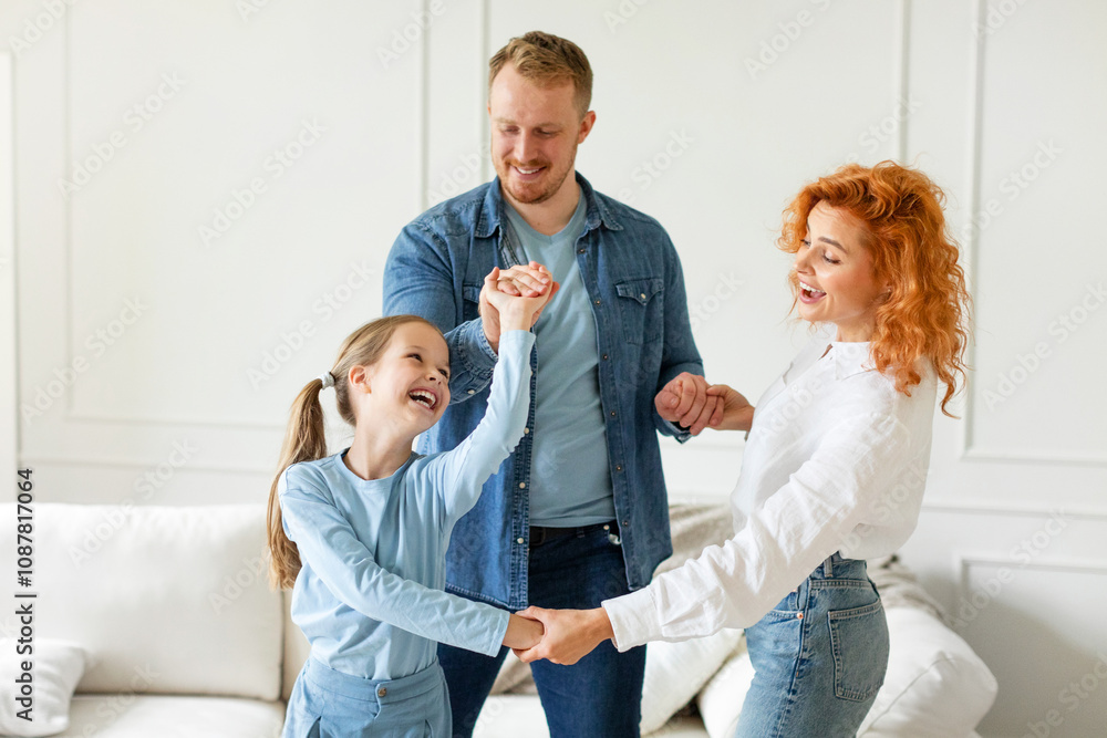 Family of three having fun, laughing and enjoying time at home, dancing together and holding hands, living room interior, free space Family of three having fun, laughing and enjoying time at home, dancing together and holding hands, living room interior, free space