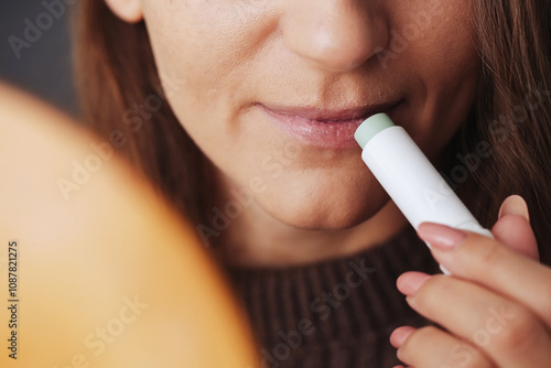 Woman using petrolatum on her mouth. Closeup lips background. Applying lip salve on lips with lipstick. Beauty background. Young girl skin care. Cosmetics for moisturize. Happy woman smile. photo