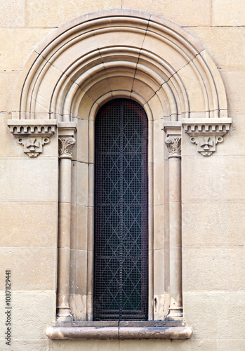 A detailed stone window featuring ornate carvings and a metal grid