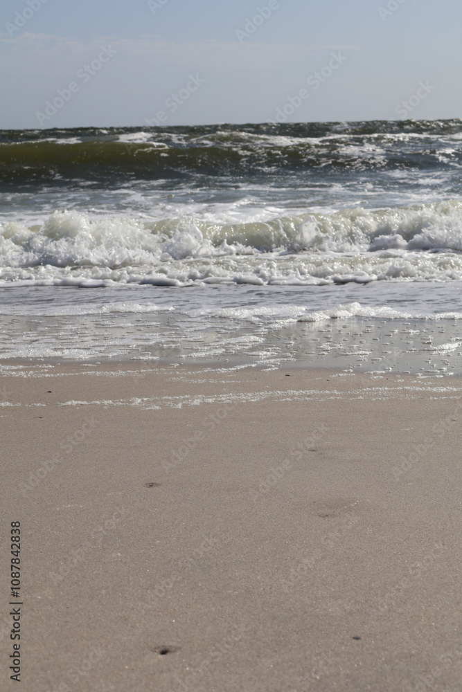 Waves breaking gently onto a smooth sandy shore under a clear sky, showcasing the peaceful interaction between water and sand. Waves breaking gently onto a smooth sandy shore under a clear sky, showcasing the peaceful interaction between water and sand.