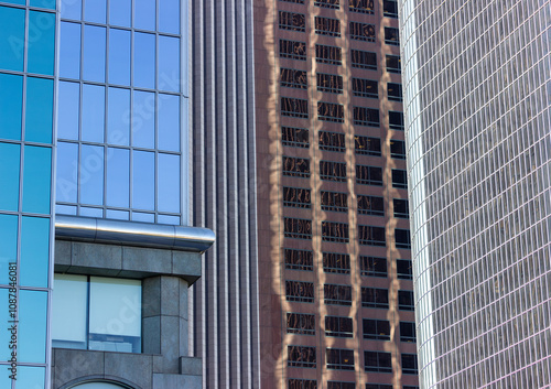 Obraz na płótnie A close-up view of modern office buildings in downtown Los Angeles. The buildings feature sleek glass facades that reflect the surrounding structures, creating an intricate pattern of reflections. w salonie