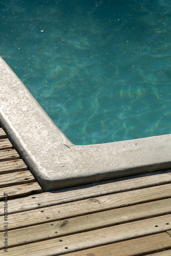 A detailed close-up of a pool with shimmering water, reflecting sunlight. The clean blue tiles and ripples create a relaxing and refreshing ambiance.