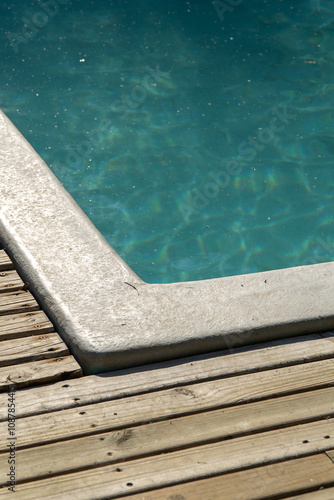 Obraz na płótnie A detailed close-up of a pool with shimmering water, reflecting sunlight. The clean blue tiles and ripples create a relaxing and refreshing ambiance. w salonie