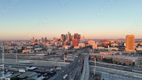 Aerial static view of  downtown Los Angeles at sunrise and clear sky with commuting cars, trains and trucks.