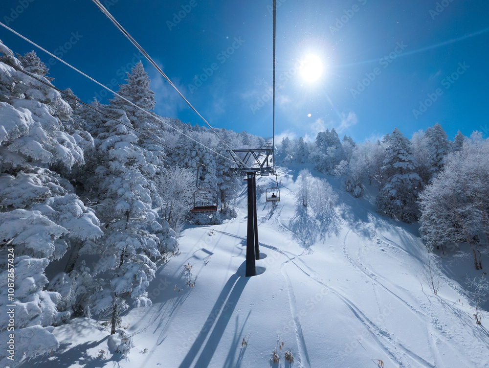 First person view of a ski chairlift heading up a mountain on a sunny day (Shibutoge, Yokoteyama, Japan) First person view of a ski chairlift heading up a mountain on a sunny day (Shibutoge, Yokoteyama, Japan)