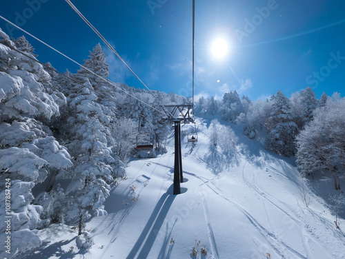 First person view of a ski chairlift heading up a mountain on a sunny day (Shibutoge, Yokoteyama, Japan) photo