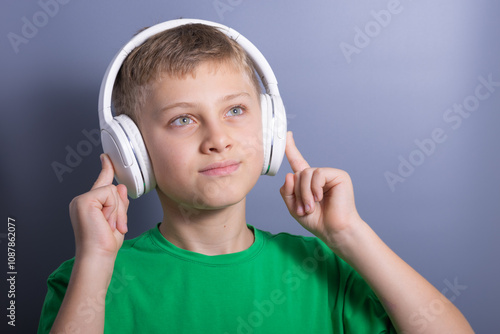 boy teenager listening music in wireless headphones isolated on grey background