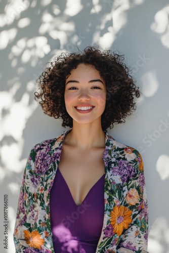 Cheerful woman with curly hair wearing floral shawl enjoying a sunny day outd...