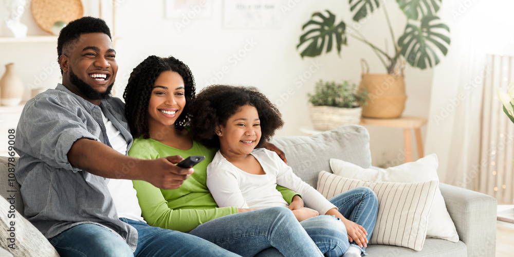 Smiling african american family relaxing and watching tv in living room, staying at home during quarantine, happy father switching channels Smiling african american family relaxing and watching tv in living room, staying at home during quarantine, happy father switching channels