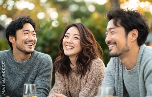 Group of friends enjoying laughter and good company during a cozy outdoor gat...