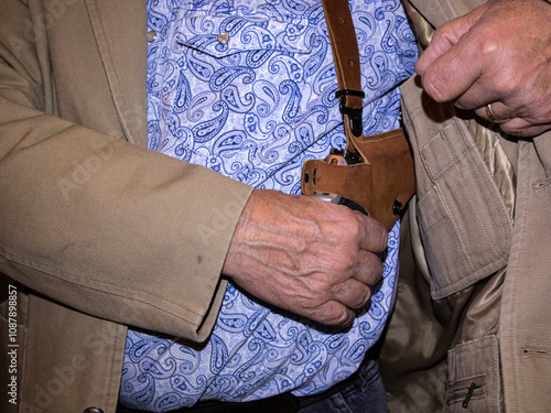 A man reaches for a pistol in his shoulder holster for protection.