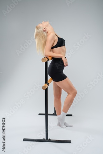 Young woman practicing ballet poses against a minimalist gray backdrop