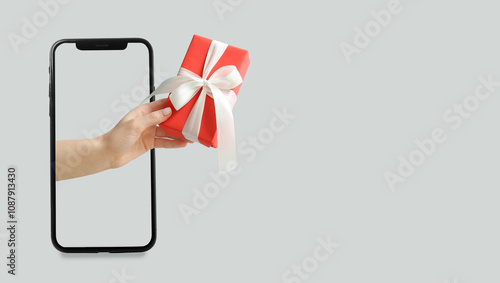 Canvas-taulu Hand with Christmas gift coming out of phone screen on light background with spa