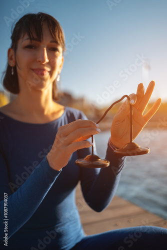 person holding tibetian tingsha bell instrument for vibration and sound healing therapy, ting-sha cymball body and mind recovery technique, woman meditation and spirituality concept photo