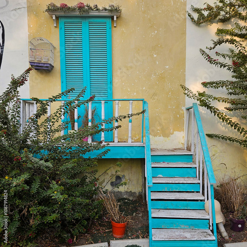 Charming vintage house with a colorful facade, blue shutters, and a wooden balcony. Perfect for nostalgic, vintage, and rustic themes.