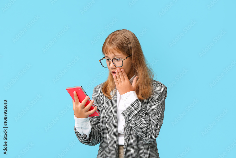 Portrait of shocked teenage office worker with calculator on blue background Portrait of shocked teenage office worker with calculator on blue background