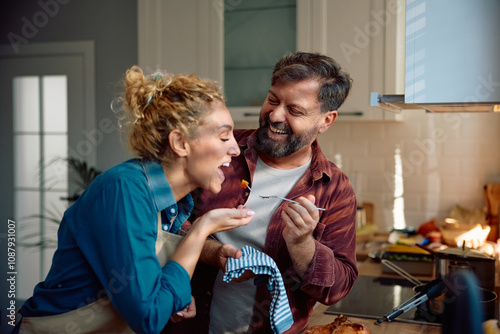 Cheerful couple having fun while cooking together in kitchen. photo