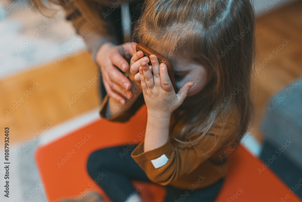 Fototapeta premium A child holds a smartphone, showing curiosity and playfulness in exploring modern technology within a familiar setting, highlighting engagement and discovery.