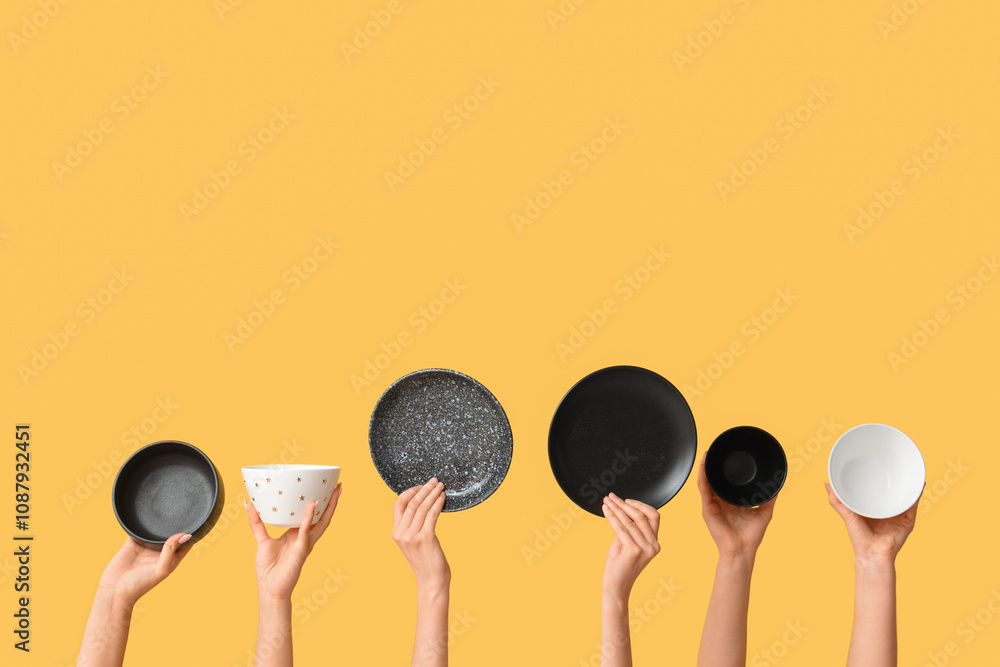 Hands holding empty plates on yellow background Hands holding empty plates on yellow background