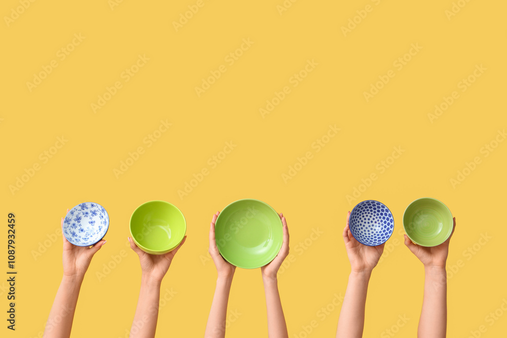 Hands holding empty plates on yellow background Hands holding empty plates on yellow background