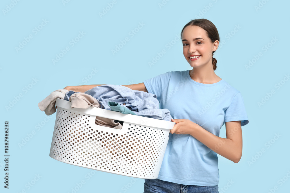Beautiful young happy woman with basket of clean laundry on blue background Beautiful young happy woman with basket of clean laundry on blue background