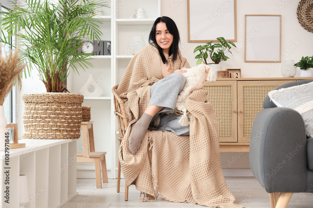 Beautiful young happy woman with warm plaid sitting on armchair at home Beautiful young happy woman with warm plaid sitting on armchair at home