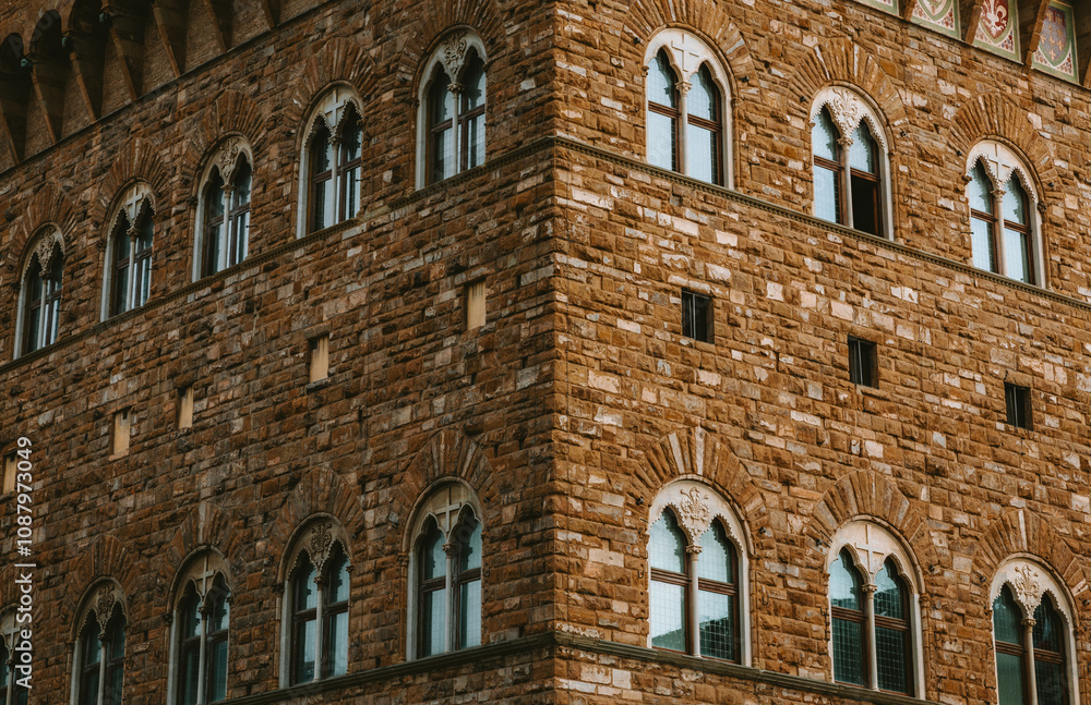 Sunlight illuminates the corner and facade of a building, showcasing its beautiful arched windows and intricate brickwork, a testament to florence's rich history and architectural prowess Sunlight illuminates the corner and facade of a building, showcasing its beautiful arched windows and intricate brickwork, a testament to florence's rich history and architectural prowess