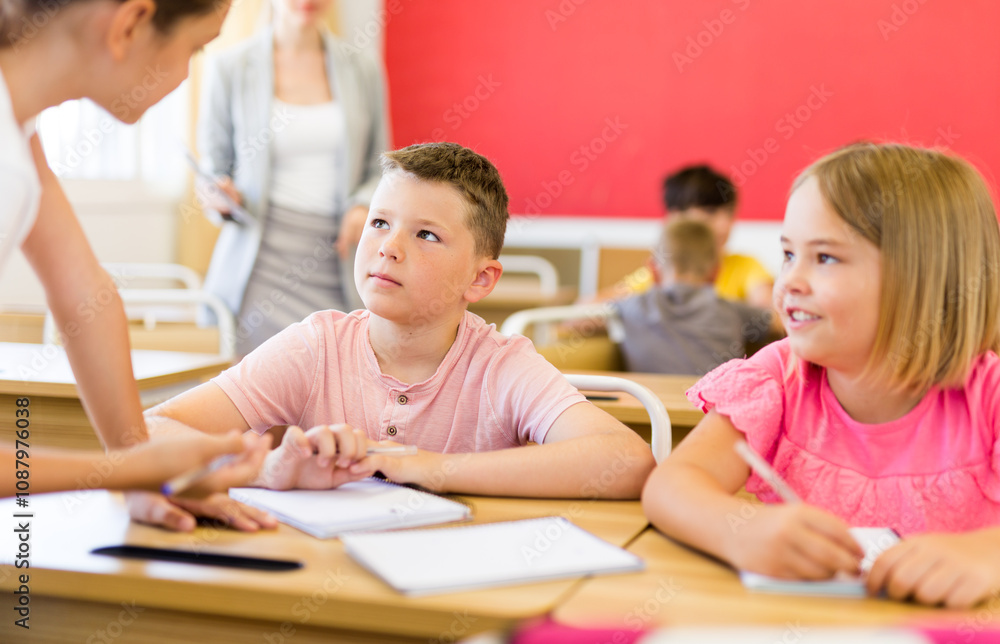 Focused tweens working in small groups during lesson at school, discussing assignment given by teacher. Teamwork concept Focused tweens working in small groups during lesson at school, discussing assignment given by teacher. Teamwork concept