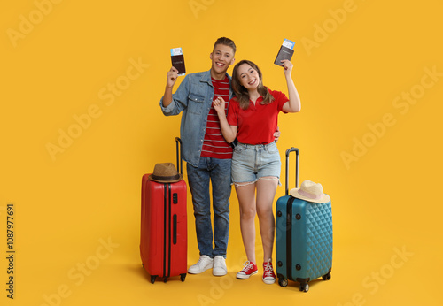 Fényképezés Happy travellers with passports, tickets and suitcases on yellow background