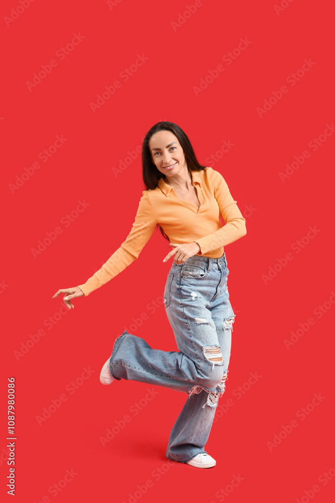 Fototapeta premium Happy middle-aged woman dancing on red background