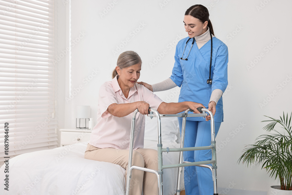 Fototapeta premium Nurse helping senior woman with walking frame in clinic