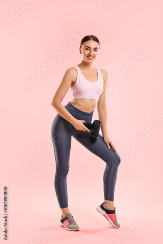 Woman using percussive massager to relax thigh muscles on pink background