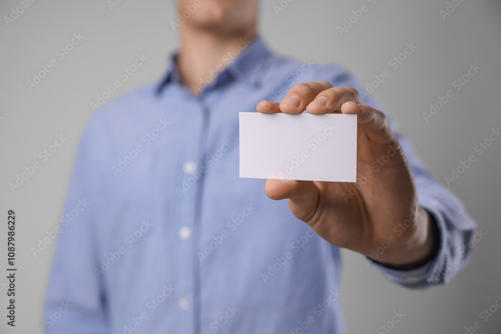 Man holding blank business card on grey background, closeup. Mockup for design Man holding blank business card on grey background, closeup. Mockup for design