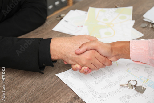 Real estate agent shaking hands with client at wooden table, closeup photo