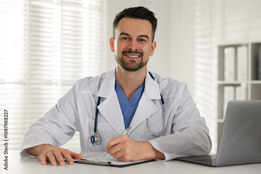 Smiling doctor with clipboard at table in clinic Smiling doctor with clipboard at table in clinic