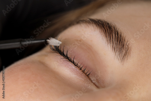 Brushing woman's lashes after lamination procedure, closeup