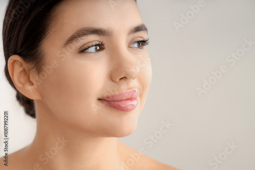 Beautiful young woman with soft lips on light background, closeup