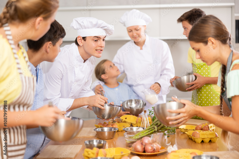 Teenage children are interested in learning in culinary courses under the supervision of two adult chefs Teenage children are interested in learning in culinary courses under the supervision of two adult chefs