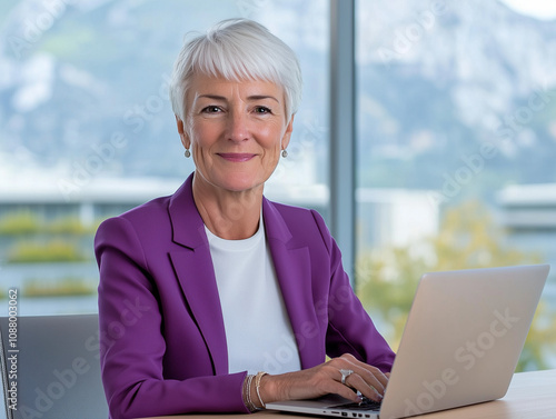 Femme de 50 à 60 ans devant un ordinateur portable de bureau : portrait d'une salariée au travail, sénior et femme dans le monde de l'entreprise