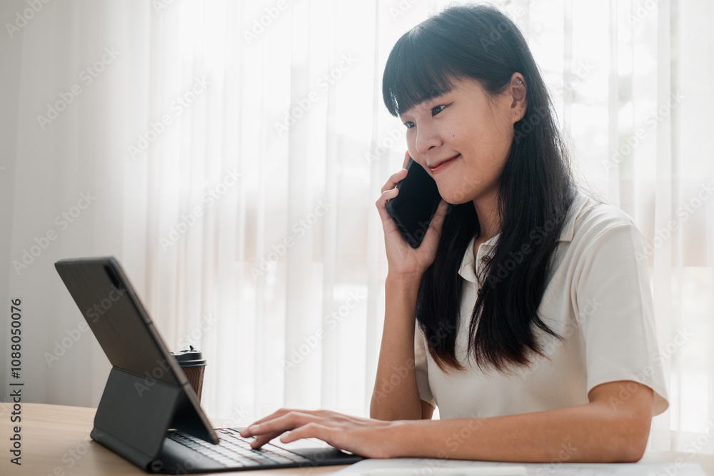 Young Woman Working from Home on Laptop While Talking on Phone in Bright Modern Room Young Woman Working from Home on Laptop While Talking on Phone in Bright Modern Room