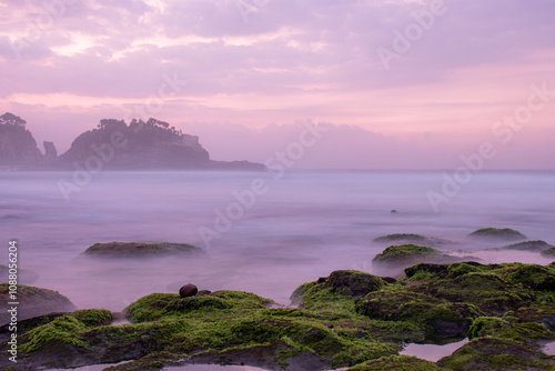 the beautiful view of a tropical beach in the morning, with white sand and coral rocks hit by ocean waves. Landscape images are taken with slow speed technique.