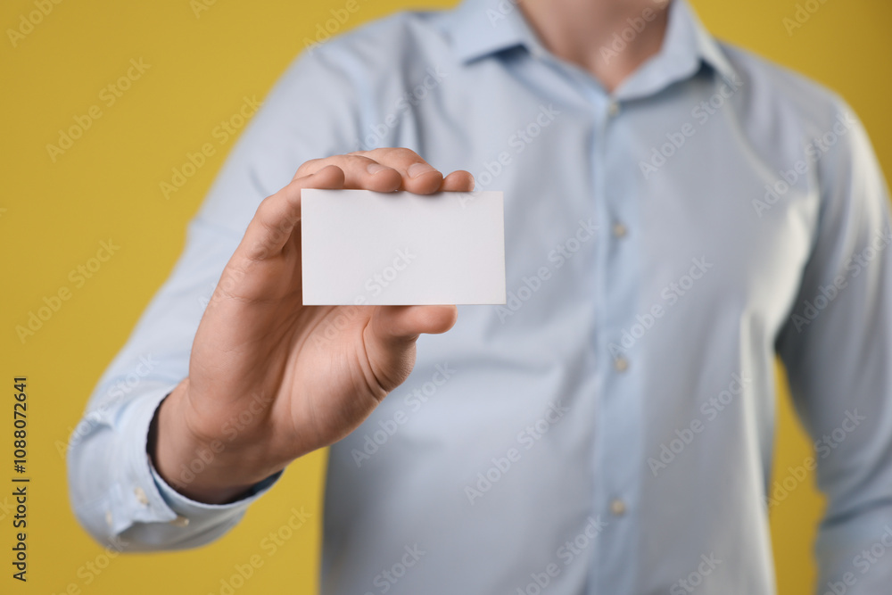 Man holding blank business card on yellow background, closeup. Mockup for design Man holding blank business card on yellow background, closeup. Mockup for design
