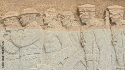 Canvastavla A stone relief shows a group of WWI soldiers and sailors in uniform, walking in unison with detailed expressions and attire, symbolizing unity and service in a historical commemorative artwork