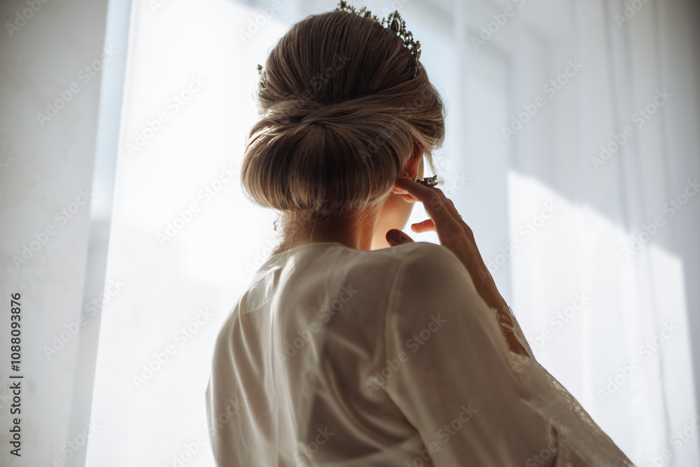 Fototapeta premium young blonde bride with elegant hairstyle looking out the hotel window before wedding, bride morning concept