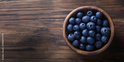 Blueberries in a circular wooden bowl on a wooden surface copy space.