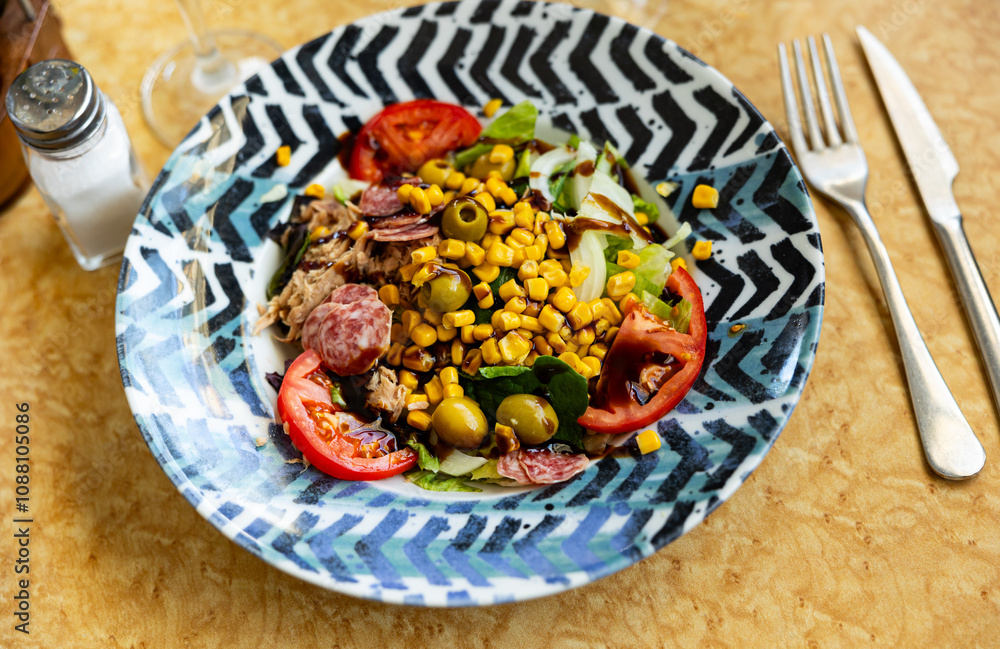 Appetizing catalan salad with sausages, tomatoes and lettuce served on platter.. Appetizing catalan salad with sausages, tomatoes and lettuce served on platter..