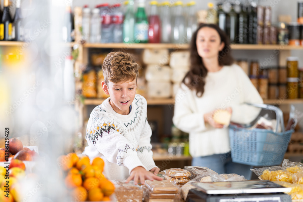 Boy buyer chooses different sweets in christmas decorated grocery store Boy buyer chooses different sweets in christmas decorated grocery store