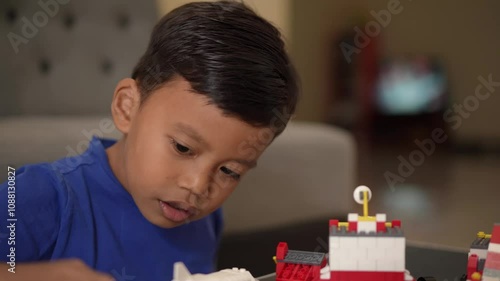 Portrait of an Indonesian boy assembling a toy while playing at home.