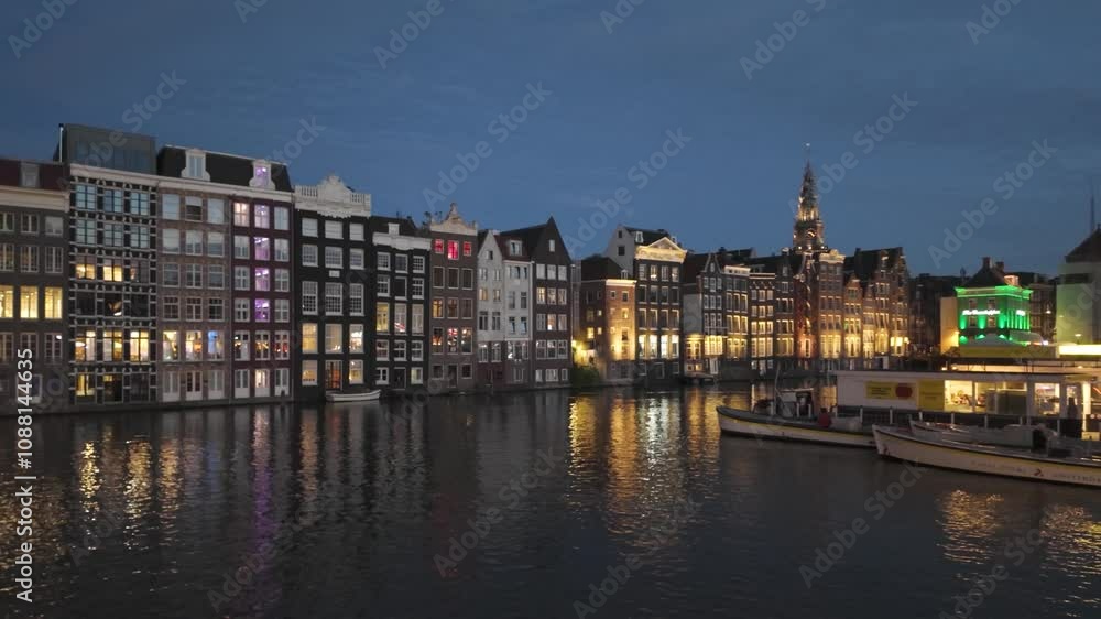 Cityscape of Amsterdam at night, buildings and lights reflecting on water, calm and scenic, establishing pan right Cityscape of Amsterdam at night, buildings and lights reflecting on water, calm and scenic, establishing pan right