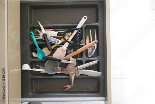 Close up of messy kitchen utensil drawer.